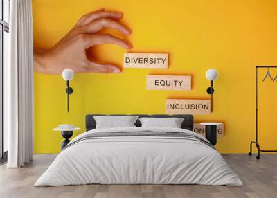 Hands holding wooden block with DEIB text or Diversity, Equity, Inclusion and Belonging on yellow background. Wall mural