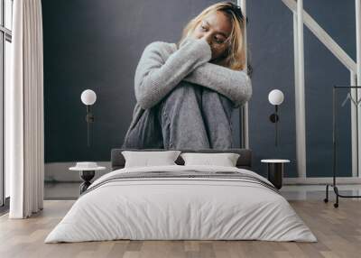 Sad and depressed young woman sitting on the home floor, sad mood,feel tired, lonely and unhappy concept. Wall mural