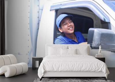 Smiling delivery man sitting in the car as a driver Wall mural