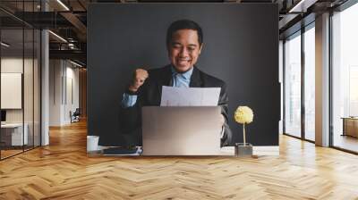 Success businessman clenched his fists while looking at business reports Wall mural