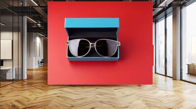 sporty sunglasses in a blue leather gift box on a solid red background Wall mural