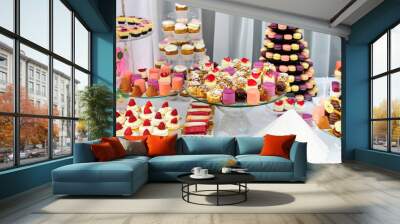 Wedding decoration with colorful cupcakes, eclairs, souffle, meringues, muffins and macarons. Elegant and luxurious event arrangement with sweets. Wedding dessert table Wall mural