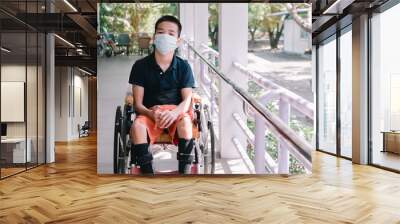 Asian special child on wheelchair wearing a protection mask against PM 2.5 air pollution and flu Covid 19 or Coronavirus on public path background, N95 to prevent the spread of the virus disease 2020. Wall mural