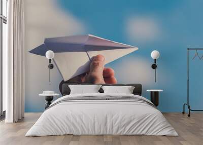 man's hand holding paper plane, blue sky background with natural light., flying to the freedom conce Wall mural