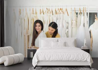 Asian female bride trying on wedding dress,Woman designer making adjustment with measuring tape in fashion studio Wall mural