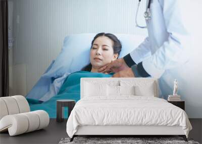 Man doctor examining asian woman patient and follow up treatment at hospital Wall mural