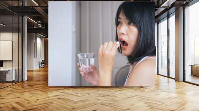 Woman sick with pill putting in her mouth,female taking medicines and a glass of water,Concept for health Wall mural