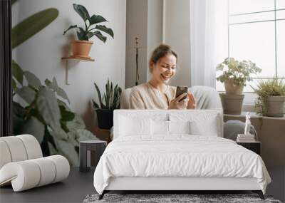 beautiful woman sitting on a sofa and using her smartphone, relaxing environment, generative ai Wall mural