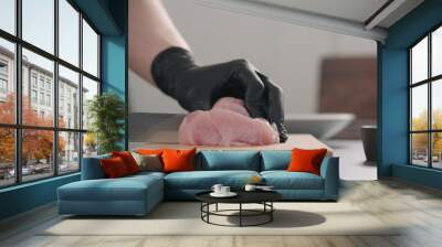 man hands in black gloves slicing turkey fillet on oak wood board Wall mural