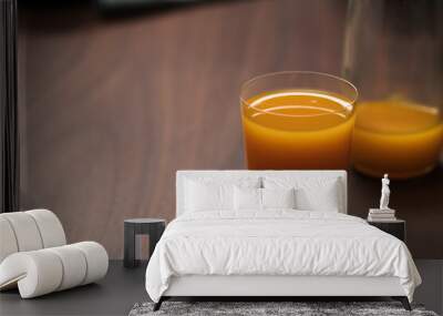 orange, pumpkin and carrot mixed juice in tumbler glass on walnut table Wall mural