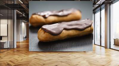 two eclairs with dark chocolate on top on slate background, shallow focus Wall mural