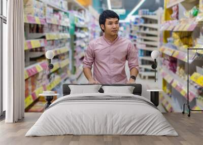 asian man with shopping cart in supermarket department store Wall mural