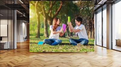 couple holding a book and resting in park Wall mural