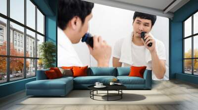 man using electric shave to shaving his face in bathroom mirror Wall mural