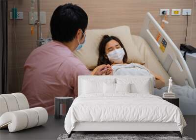 man visiting and take care female patient on bed at hospital. people must be wearing medical mask to prevention coronavirus(covid-19) pandemic. Wall mural