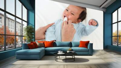 mother using finger to clean newborn baby mouth (tongue and gum) with clean gauze on bed Wall mural