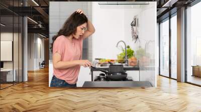 stressed woman cooking and preparing food in the kitchen at home Wall mural