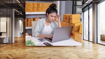 stressed woman working with laptop computer and courier parcel box at home office Wall mural