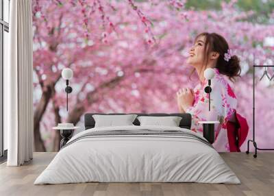 woman in yukata (kimono dress) looking sakura flower or cherry blossom blooming in garden Wall mural