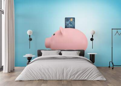 3d rendering of a pink piggy bank stands in a side view on a blue background with a credit card stuck into its coin slot. Wall mural