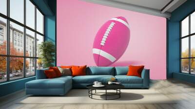 A magenta American football ball with white stripes stands on a pink background. Wall mural