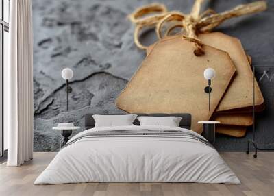 Three vintage-styled blank tags tied together with rustic string, placed on a textured dark stone surface. Ideal for rustic or antique-themed settings. Wall mural