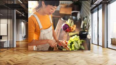 Asian woman chopping vegetables in kitchen for healthy meal prep Wall mural