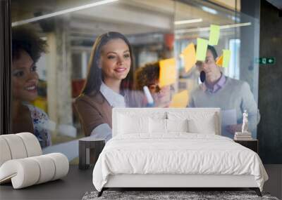 Business people putting sticky notes on a glass board in a modern office Wall mural