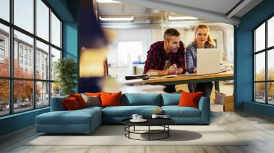 Diverse group of coworkers using a laptop in a printing press office Wall mural