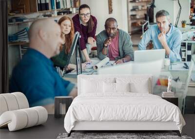 Diverse team collaboratively discussing a project in a creative office space Wall mural