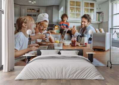 Happy family enjoying breakfast together in modern kitchen with laptop Wall mural