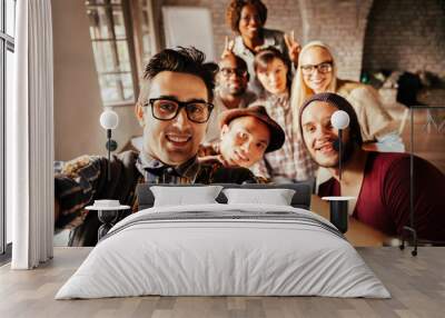 Happy multicultural team taking a group selfie in creative office Wall mural