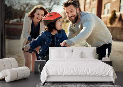 happy young boy having first bike ride with parents outside Wall mural