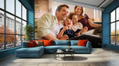 Happy young Caucasian family watching a movie together in the living room Wall mural