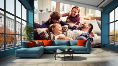 Happy young family relaxing on the couch together at home Wall mural