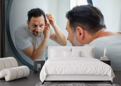 Man styling hair in front of bathroom mirror Wall mural