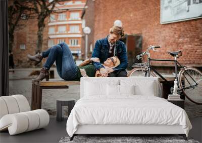 Middle aged Caucasian couple relaxing on the bench after riding a bicycle together in the city Wall mural