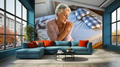 Senior woman holding shoulder in pain at home Wall mural