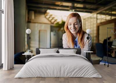 Smiling young woman using smartphone in office Wall mural