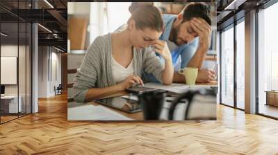 Worried young Caucasian couple going over their bills and home finances in the morning in the kitchen Wall mural