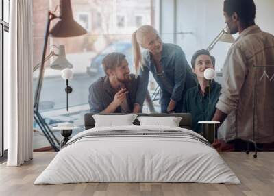 Young and diverse group of architects working on a project together in a startup company office Wall mural