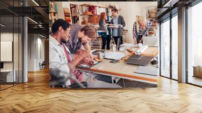 Young and diverse group of designers working on a project together in the office Wall mural