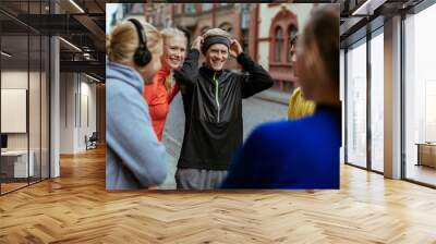 Young and diverse group of friends stretching and getting ready to exercise and jog in the city Wall mural