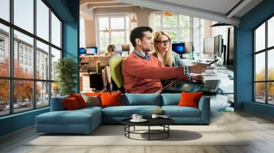 Young Caucasian coworkers using the computer together in a marketing company office Wall mural