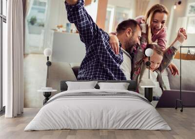 Young Caucasian family having fun and using the laptop on the couch at home Wall mural