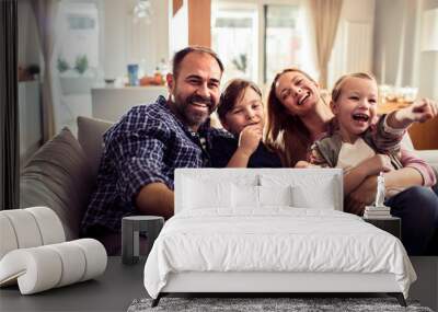 Young Caucasian family watching a movie and having fun on the couch in the living room at home Wall mural