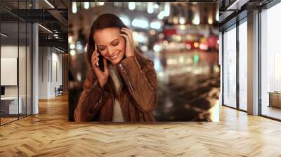 Young caucasian woman talking on her smart phone at the piccadilly circus at night in London UK Wall mural