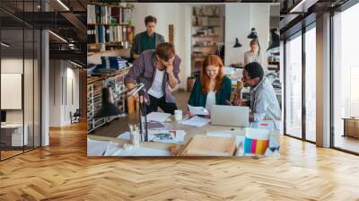 Young creative team working on project in busy design studio office Wall mural