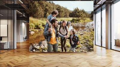 Young family hiking by a creek in the forest Wall mural