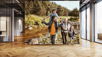 Young family hiking in the forest next to a creek Wall mural